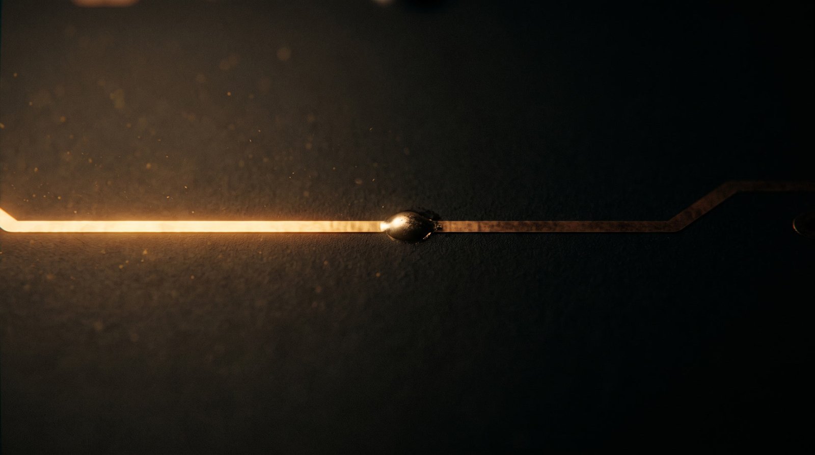 A golden circuit trace reaching a solder node and going dark, the rest of the board unlit